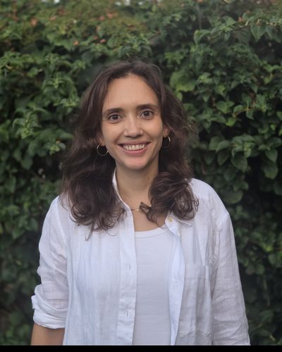 Mandy van Zwam, lachend, voor een groene haag
